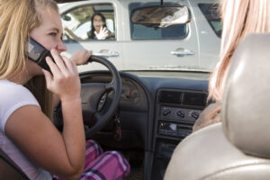 A teenage girl using her phone while driving and is going to be in a accident