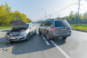 Two cars crashed on the road in autumn time.